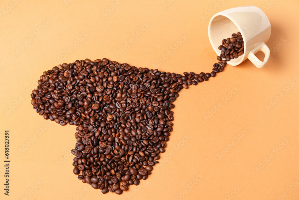 Coffee beans spilled from cup in shape of heart on orange background