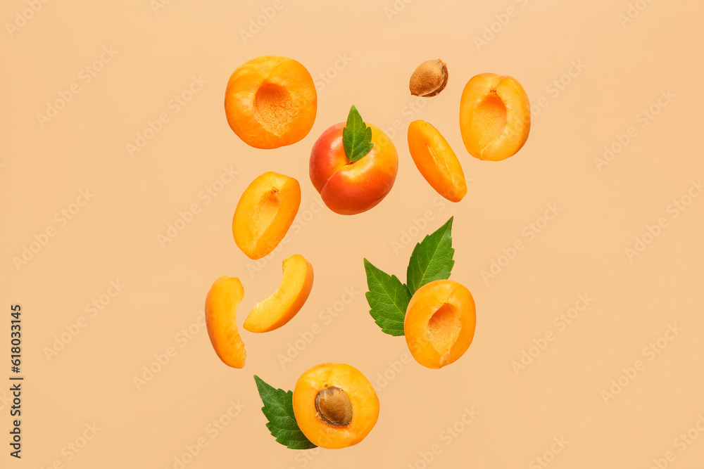 Flying fresh apricot with pieces and leaves on orange background