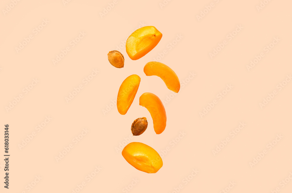 Flying pieces of fresh apricot on pink background