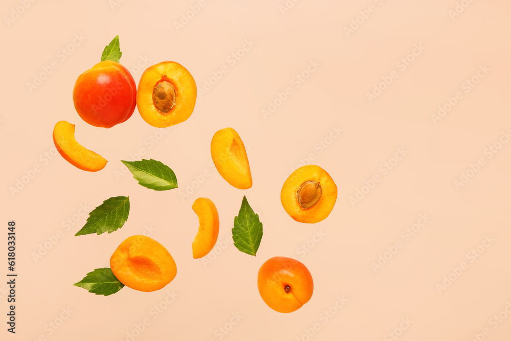 Flying fresh apricots with pieces and leaves on pink background