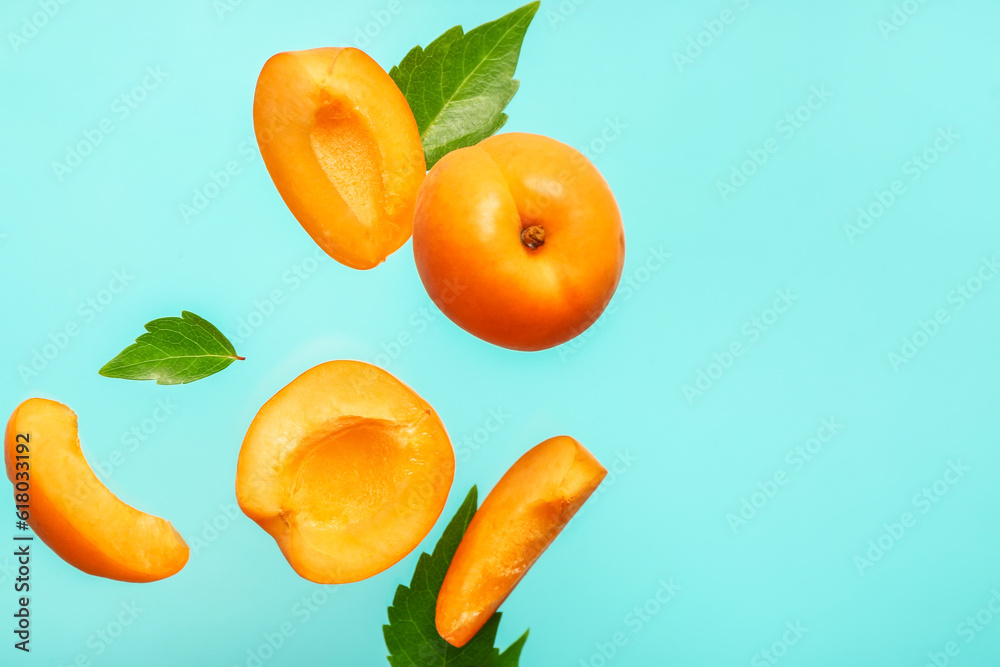 Flying fresh apricot with pieces and leaves on blue background