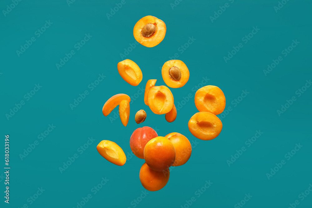 Flying fresh apricots with pieces on blue background