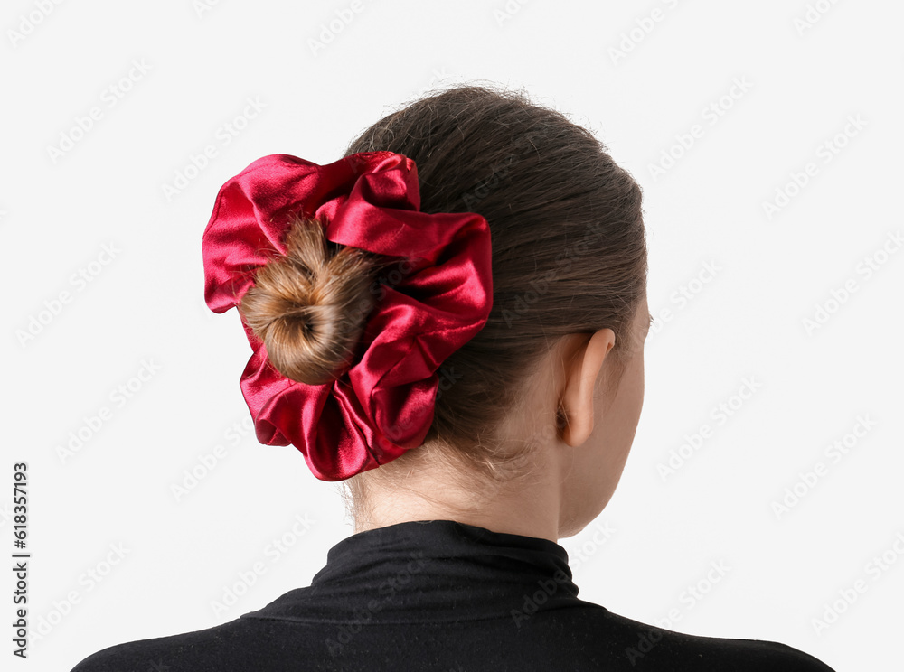 Woman with bun hairstyle and silk scrunchy on light background, back view