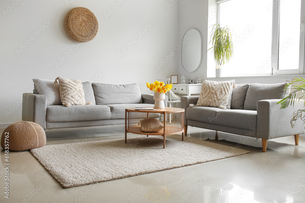 Interior of modern living room with cozy sofas and flower vase on coffee table