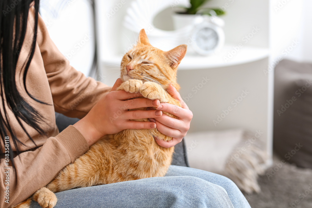 Woman with cute ginger cat at home, closeup