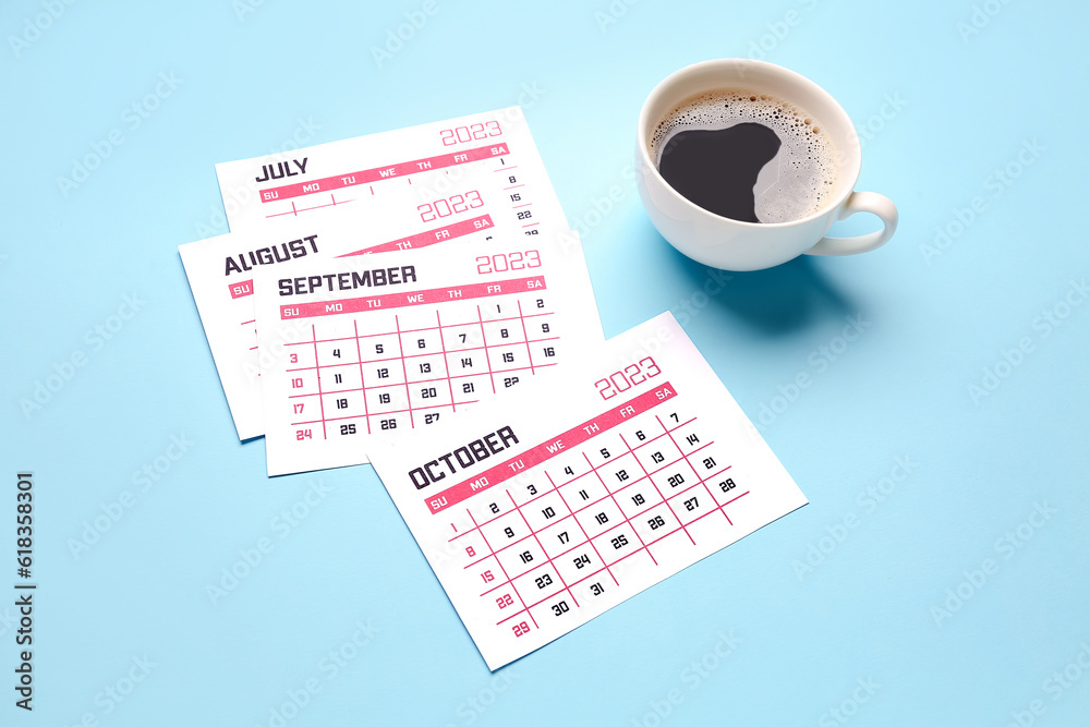 Pages of calendar and cup of coffee on blue background