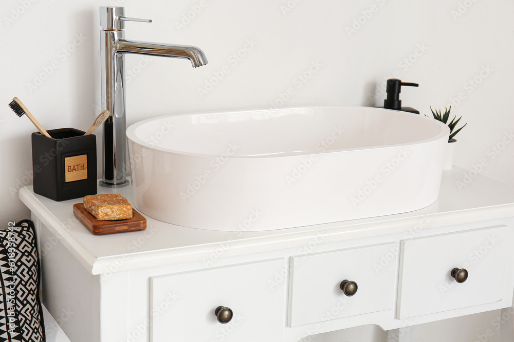 Sink with bath accessories on table near light wall in room