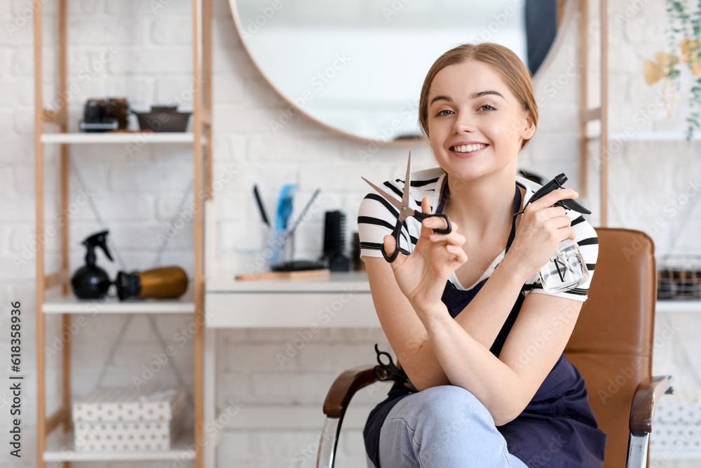 Female hairdresser with scissors and spray in beauty salon