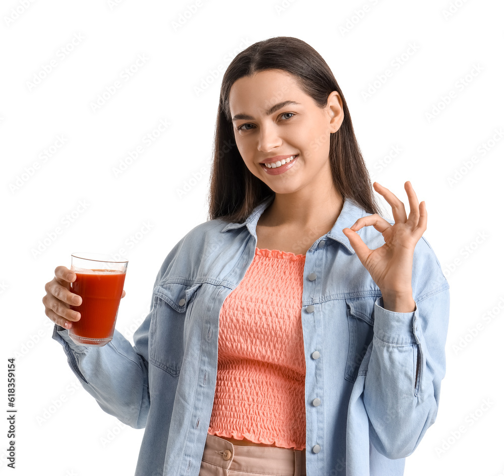 Young woman with glass of vegetable juice showing OK on white background