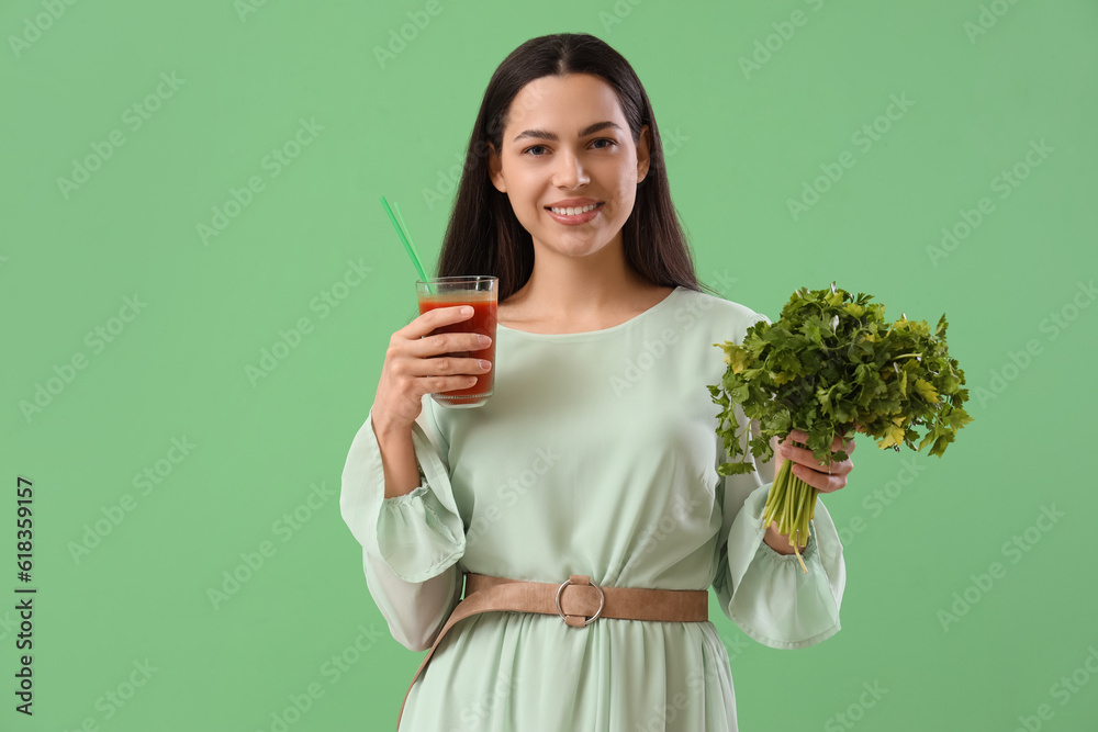 Young woman with glass of vegetable juice and parsley on green background