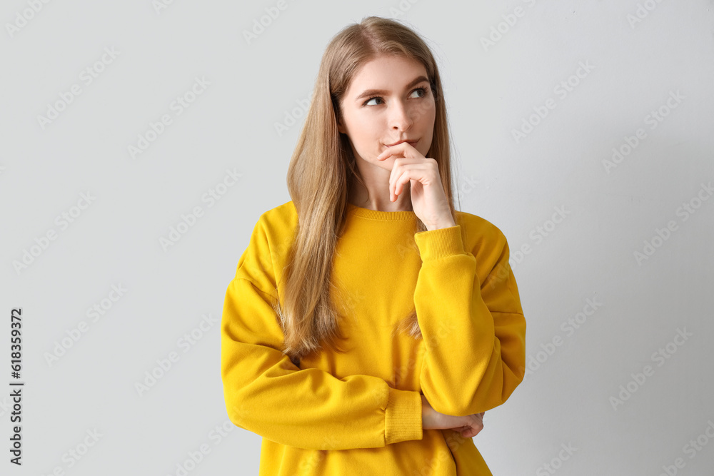 Thoughtful young woman on light background