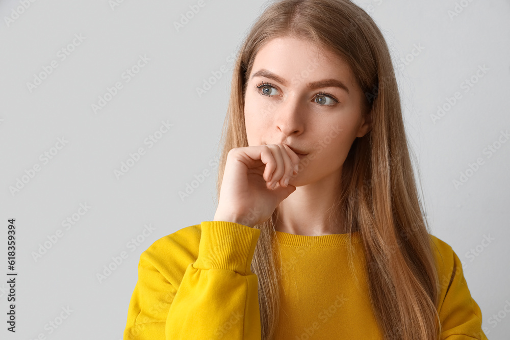 Thoughtful young woman on light background, closeup