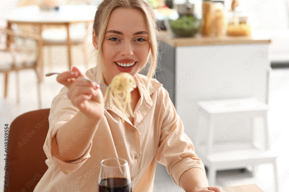 Young woman eating tasty pasta in kitchen, closeup