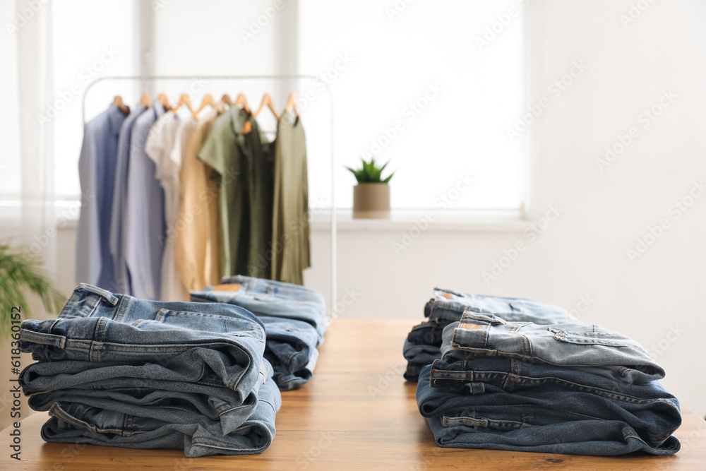 Table with stylish jeans pants in modern boutique, closeup