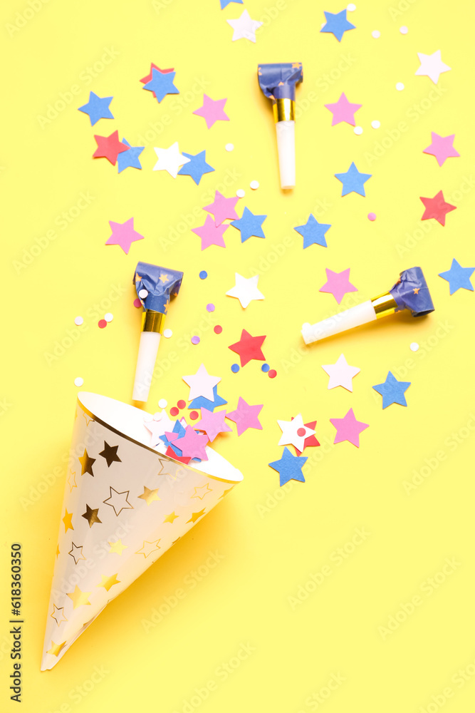 Composition with party hat and whistles on pale yellow background