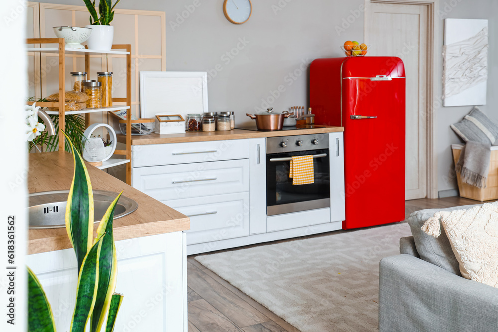 Interior of kitchen with red fridge, counters, sofa and shelving unit