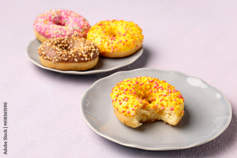 Plates with sweet donuts on light background