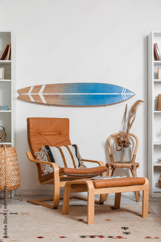 Interior of light living room with surfboard and brown armchair