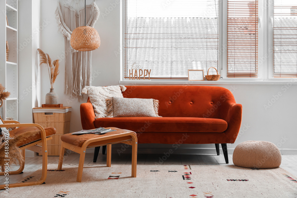 Interior of light living room with surfboard, brown sofa and armchair