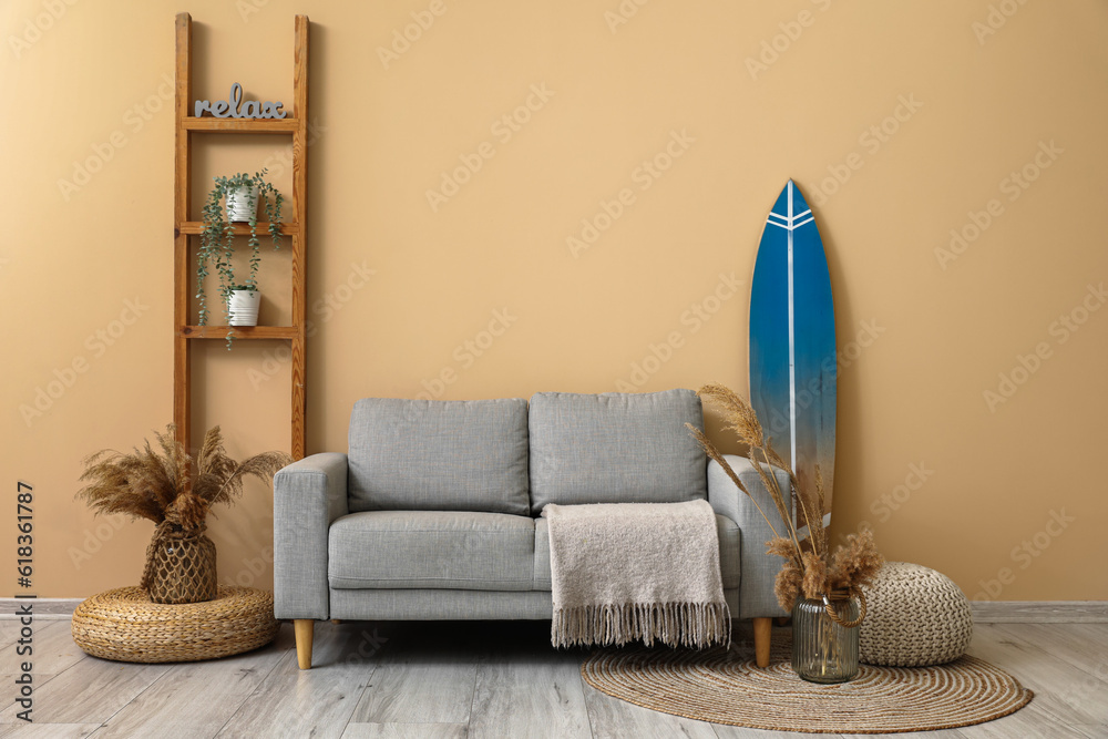 Interior of modern stylish room with surfboard, shelving unit and sofa