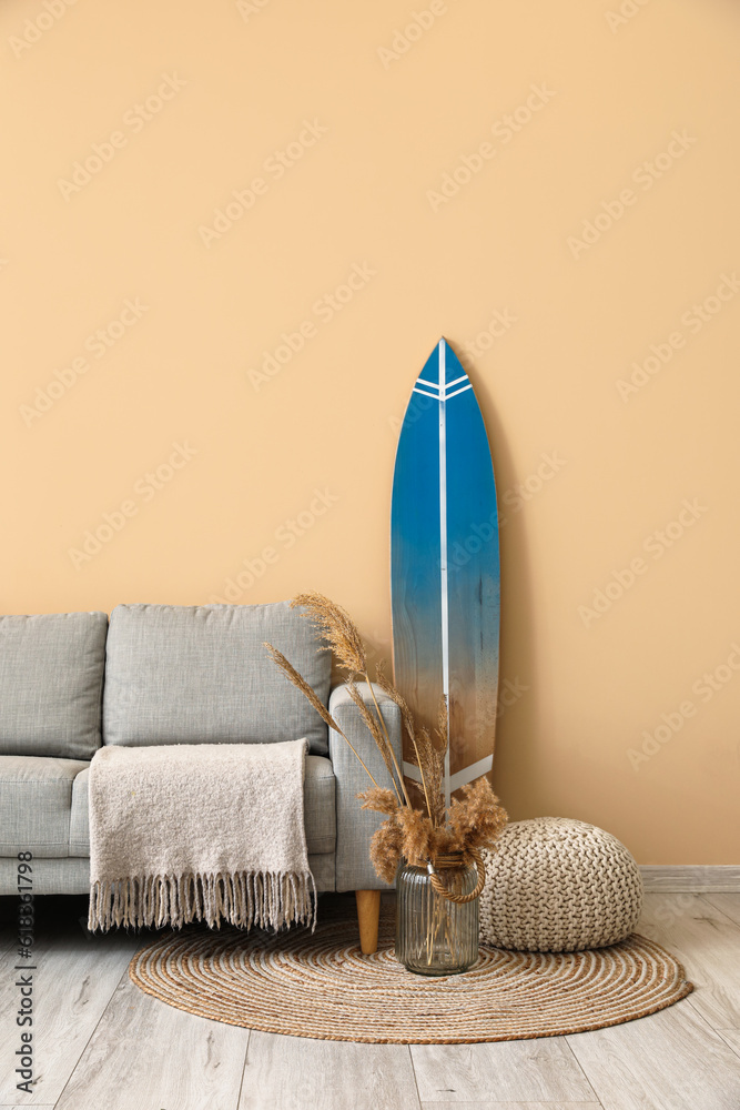 Interior of modern stylish room with surfboard, ottoman and sofa