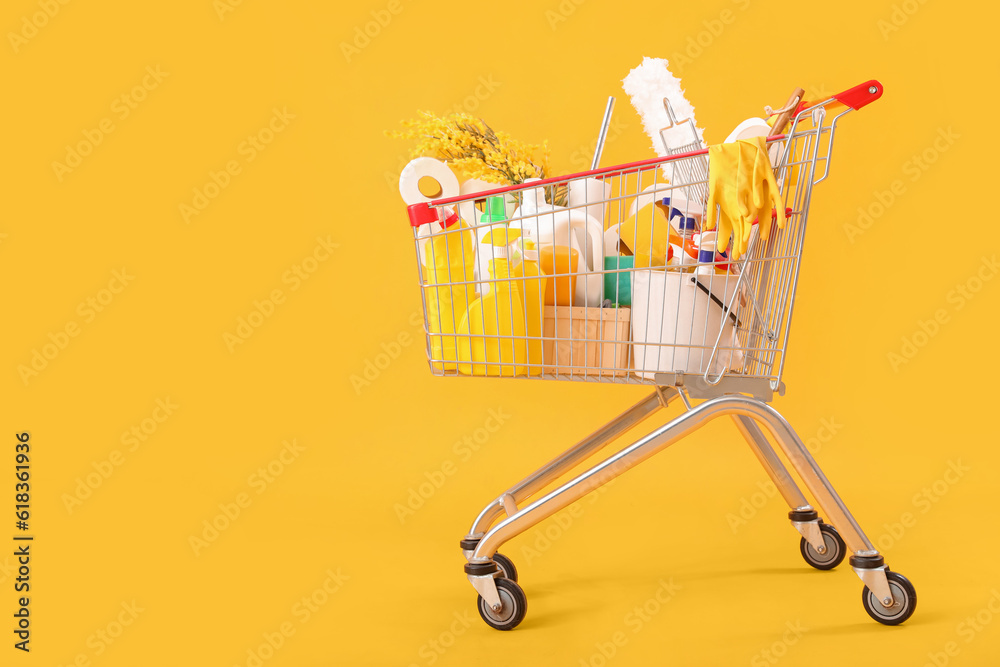 Shopping cart full of cleaning supplies with flowers on yellow background