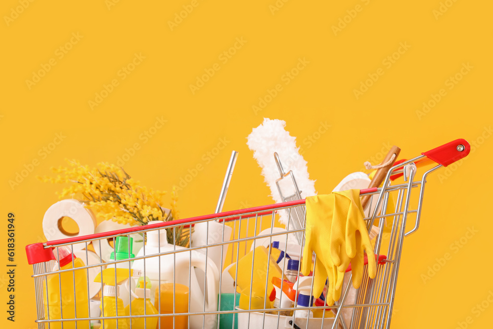 Shopping cart full of cleaning supplies with flowers on yellow background