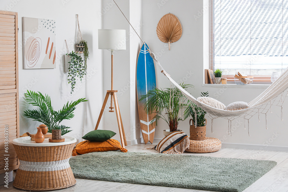 Interior of stylish living room with hammock, surfing board and soft carpet