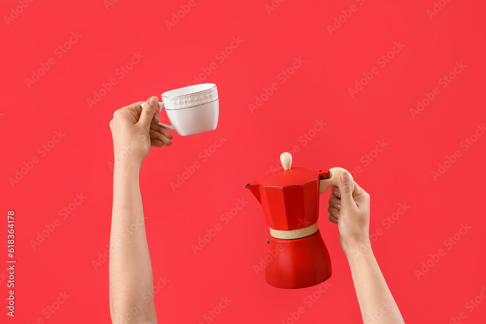 Female hands holding cup and geyser coffee maker on red background