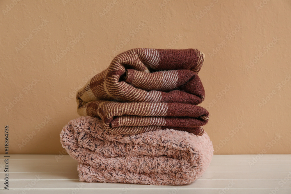 New soft folded blankets on table near beige wall