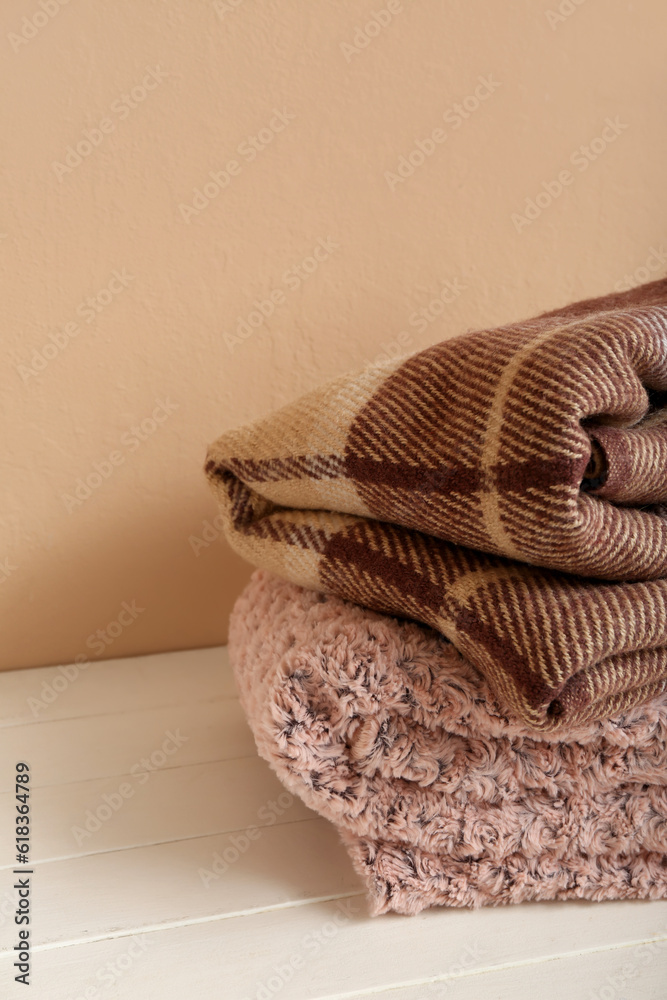 New soft folded blankets on table near beige wall