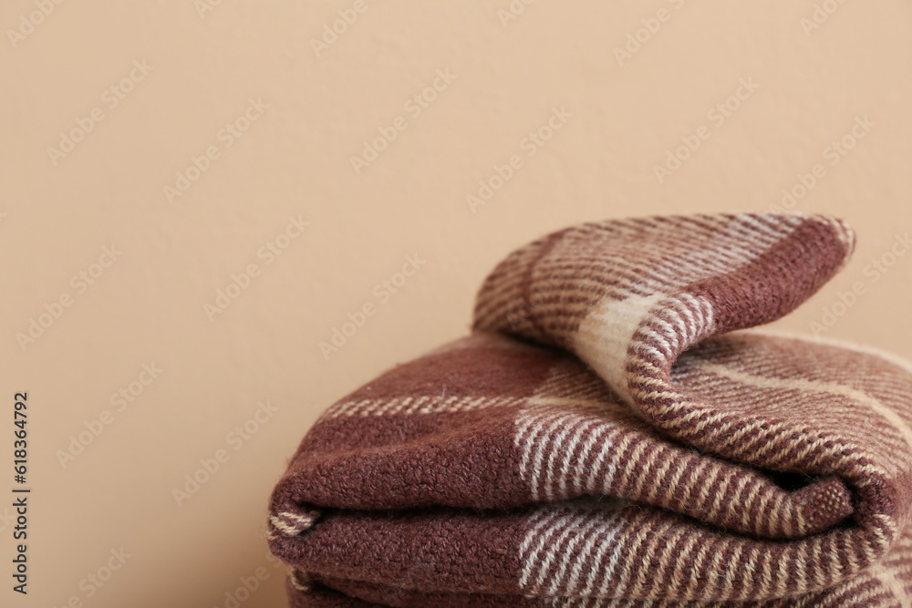 New soft folded blanket on beige background, closeup