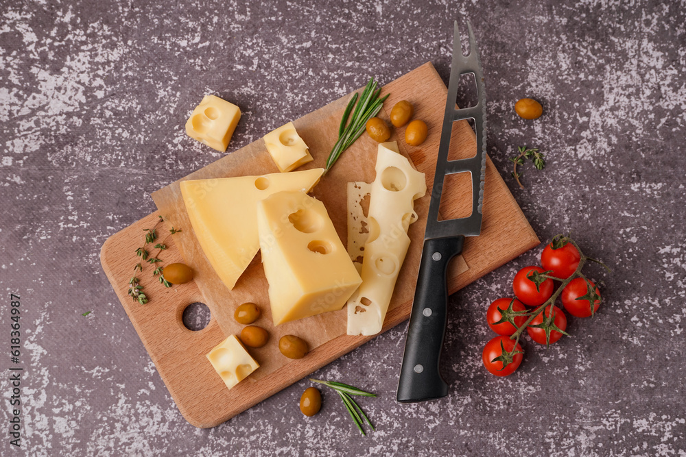 Board with pieces of Swiss cheese and olives on grey background