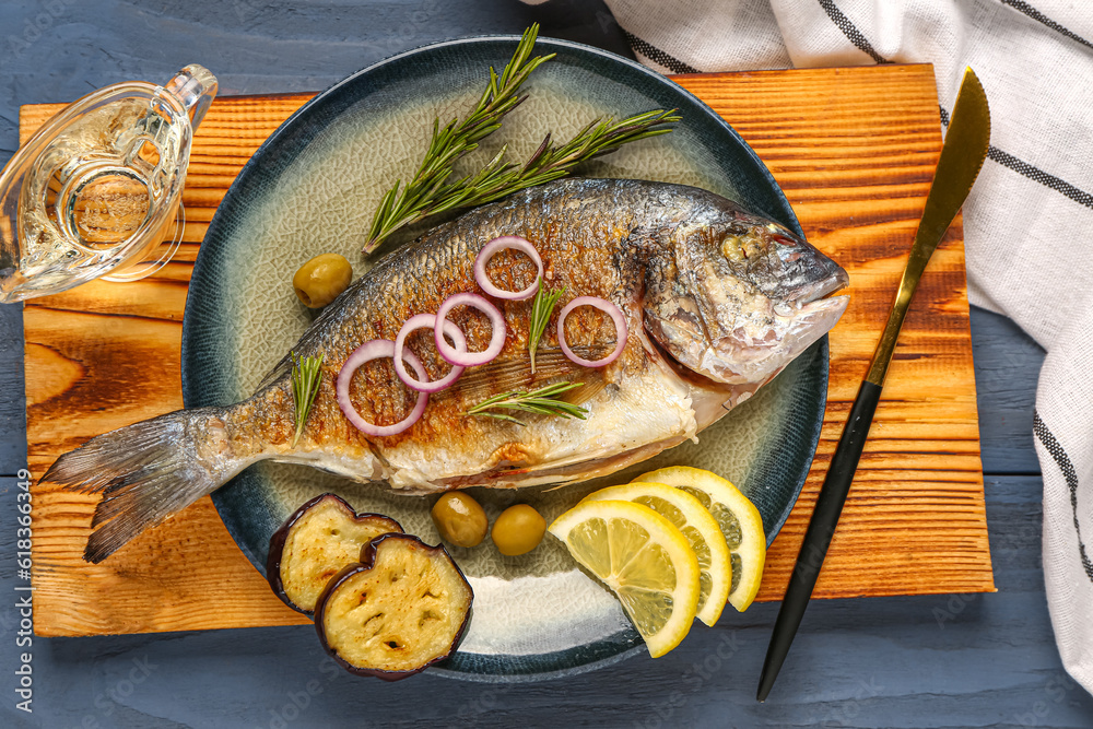 Plate with tasty grilled dorado fish on wooden background