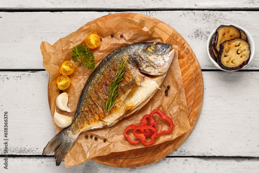 Board with tasty grilled dorado fish on light wooden background