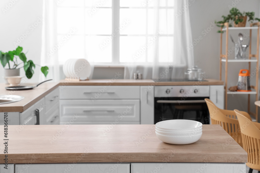 Set of clean bowls on wooden countertop in interior of light kitchen