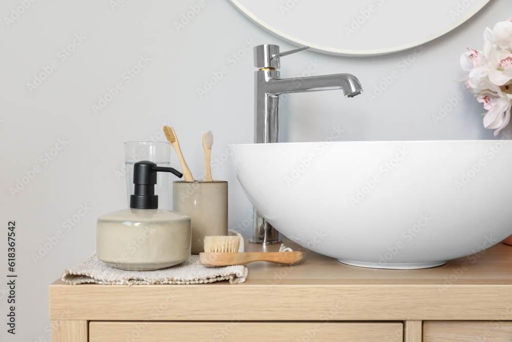 Sink bowl and bath accessories on wooden cabinet in bathroom