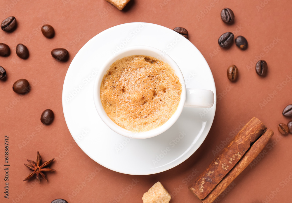 Cup of hot espresso and coffee beans on brown background