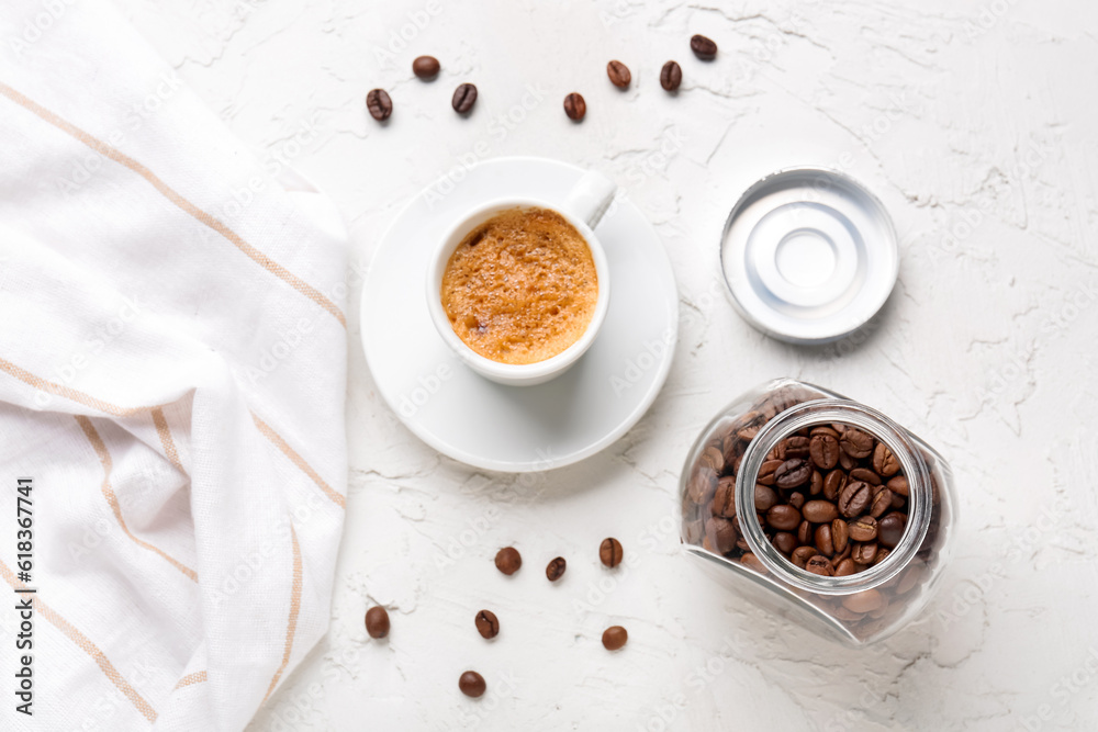 Cup of hot espresso and jar with coffee beans on white background