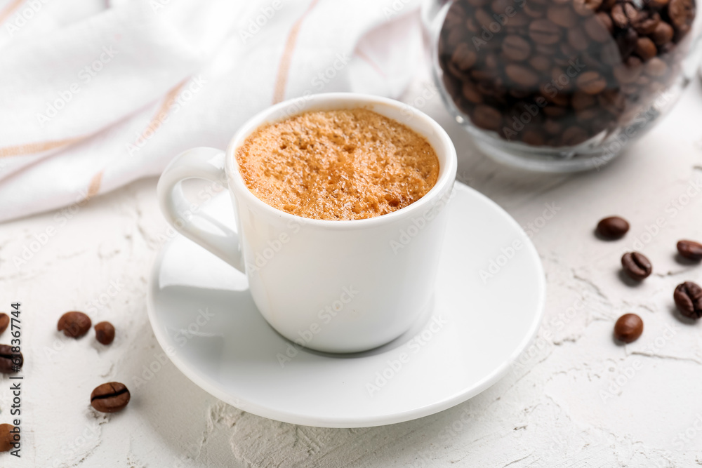 Cup of hot espresso and jar with coffee beans on white background