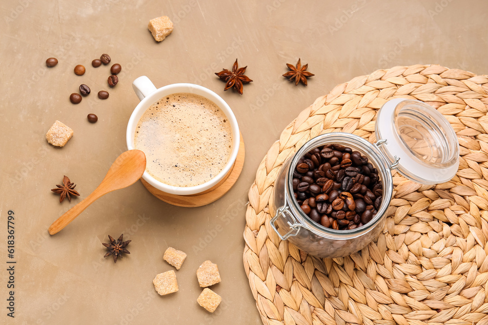 Cup of hot espresso and jar with coffee beans on brown background