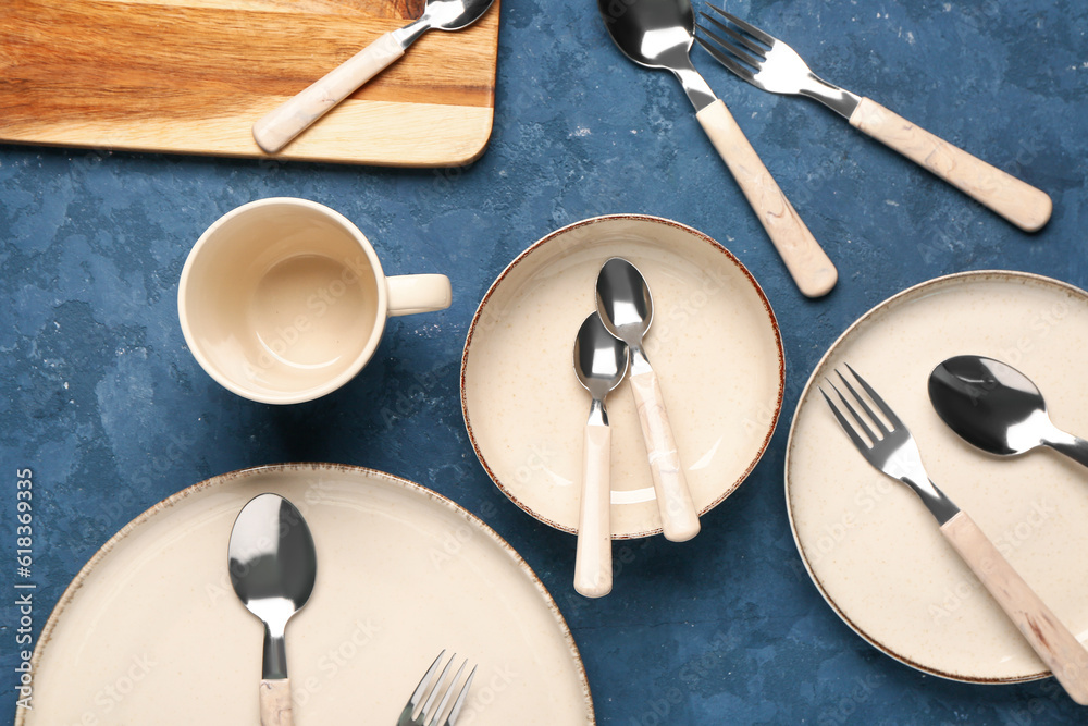 Clean plates, bowl, cup and cutlery on blue table