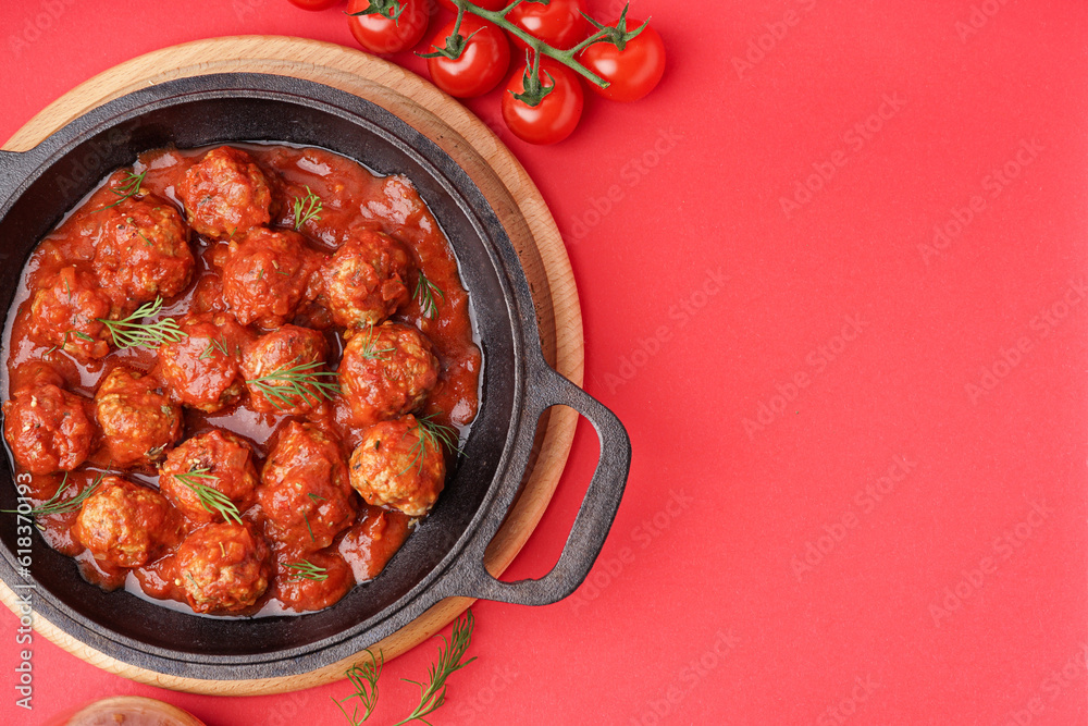 Frying pan of tasty meat balls with tomato sauce and dill on red background