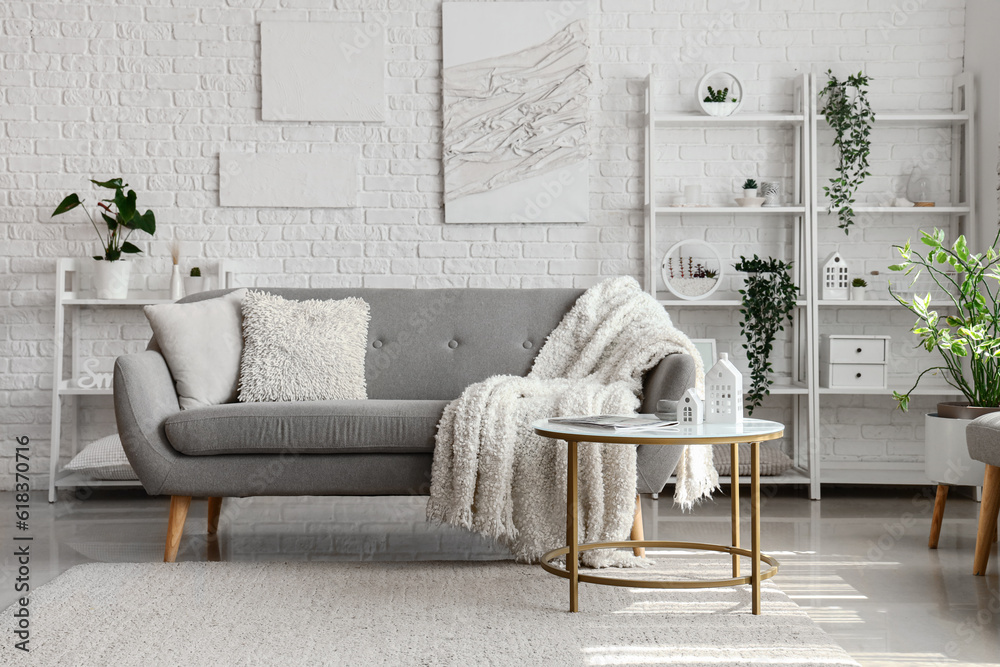 Interior of light living room with cozy grey sofa and coffee table