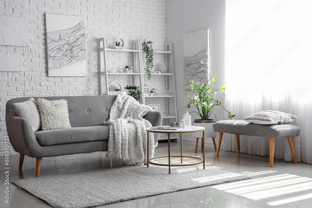 Interior of light living room with cozy grey sofa and coffee table