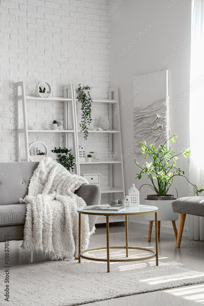 Interior of light living room with cozy grey sofa and coffee table