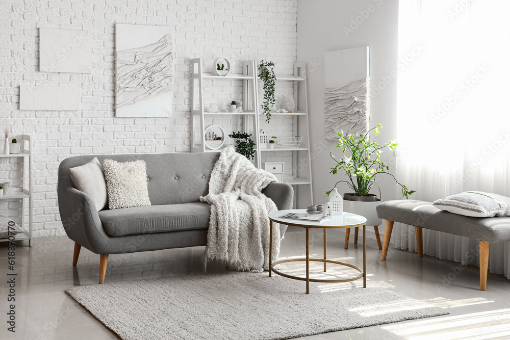 Interior of light living room with cozy grey sofa and coffee table