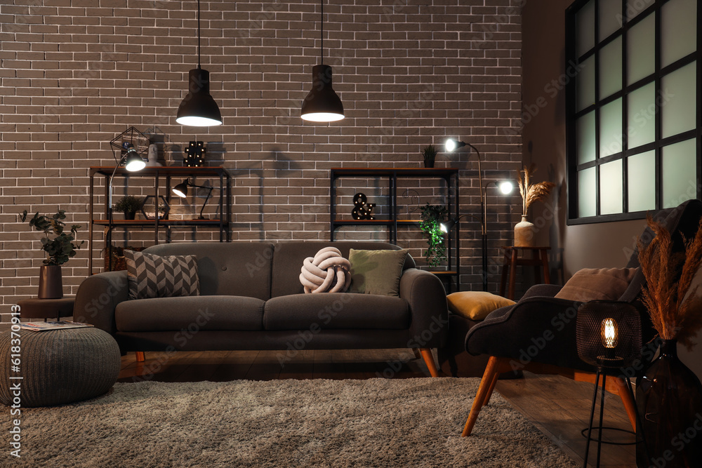 Interior of dark living room with cozy grey sofa and glowing lamps