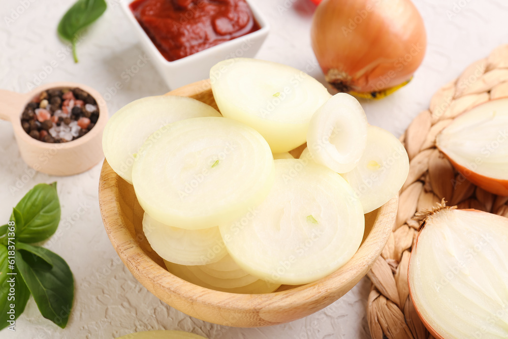 Bowl with fresh onion slices, sauce and spices on white background, closeup