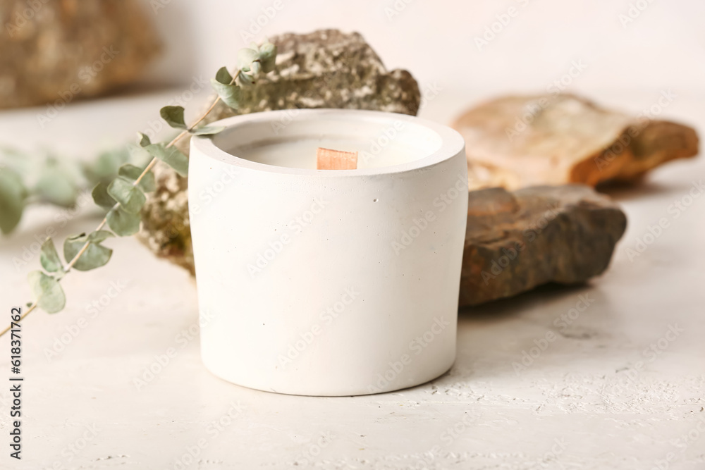 Holder with candle and stones on white background